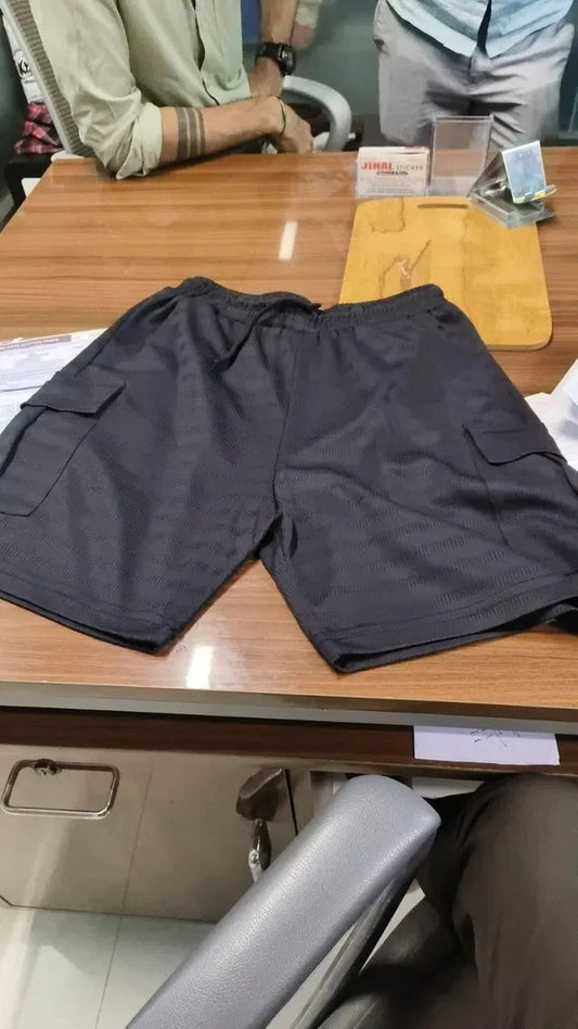 Black men's cotton cargo shorts pack displayed on wooden table with side pockets