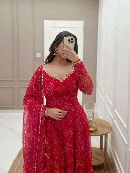 Woman wearing a red bandhani gown for women with intricate patterns and sheer sleeves