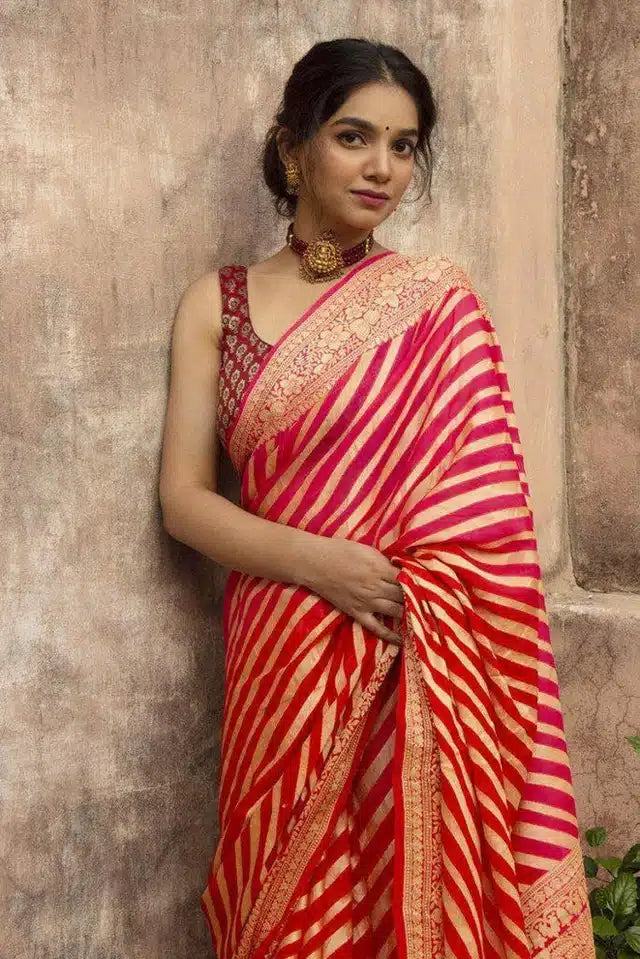 Woman wearing red and pink striped designer saree for women online with gold border and traditional jewelry