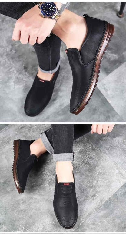 Black men leather casual shoes with brown sole worn with gray rolled jeans on concrete floor