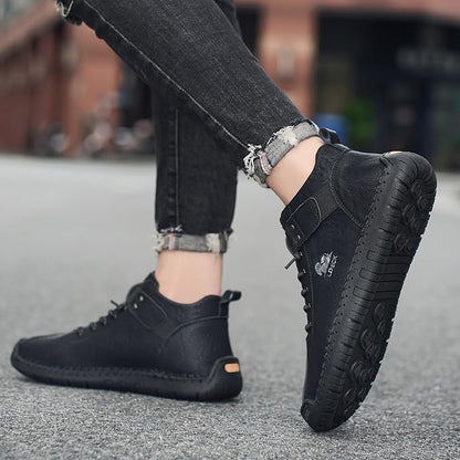 Stylish men's black boots with durable soles and lace-up design worn with rolled black jeans
