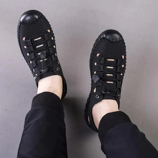 Black men's casual fashion shoes with lace-up design worn with black pants on gray background