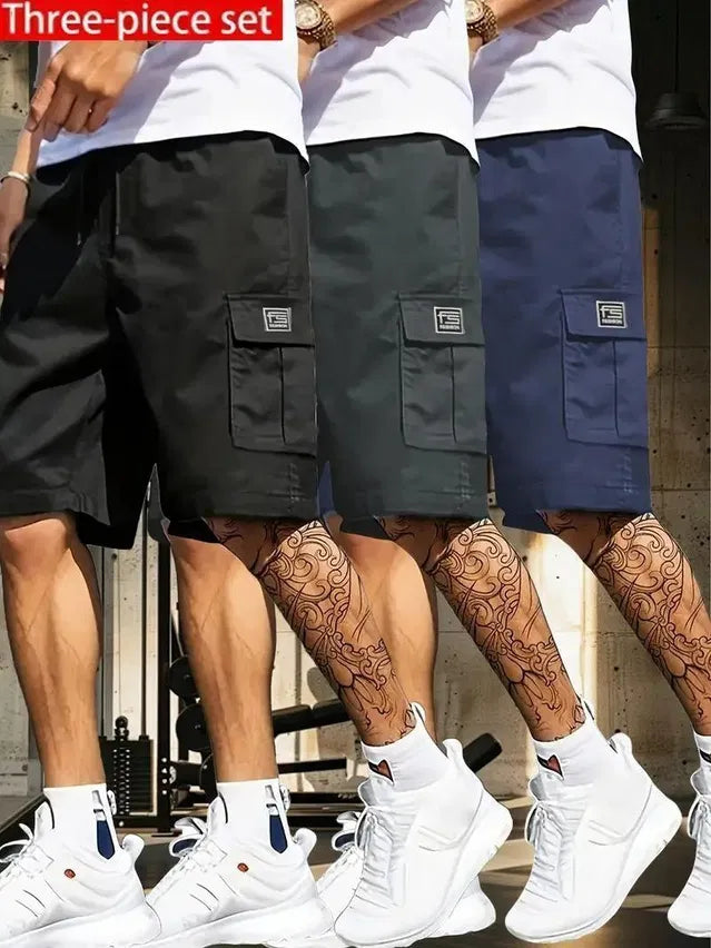 Three-piece set of men's cotton cargo shorts pack in black, dark green, and navy blue worn with white sneakers