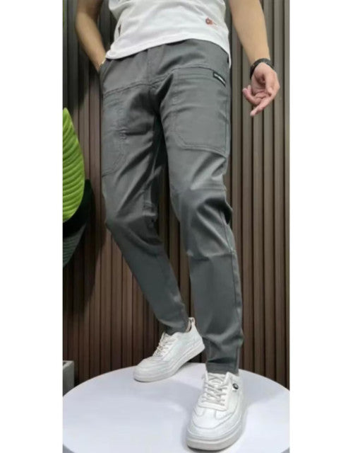 Man wearing gray men's solid joggers pack pants paired with white sneakers standing indoors