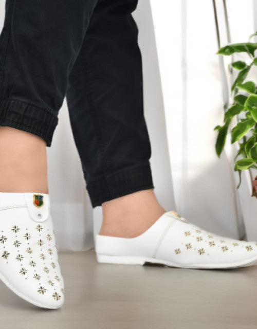 White men's stylish half loafers with gold decorative patterns worn with black pants indoors
