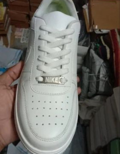 Top view of Nike Air Force white sneakers held in hand showing perforated toe and laces