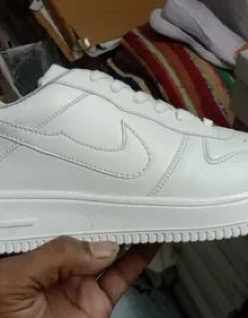 White Nike Air Force white sneakers held in hand showing side profile and sole design