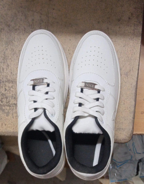 Top view of Nike Air Force white sneakers with white laces on a beige surface
