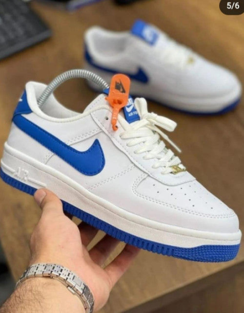 White and blue Nike sneakers held by hand with orange tag showcasing the best sneakers for men 2025