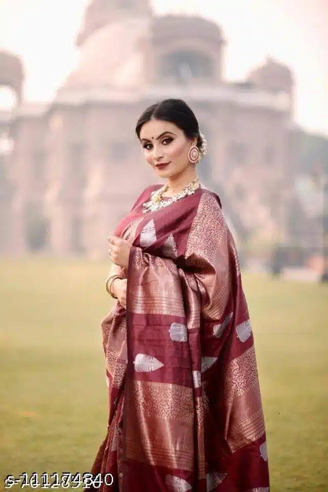 Woman wearing premium quality silk saree online in maroon and gold with traditional jewelry outdoors