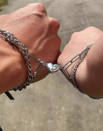Close-up of two wrists wearing a silver chain bracelet for women with a heart charm linked together