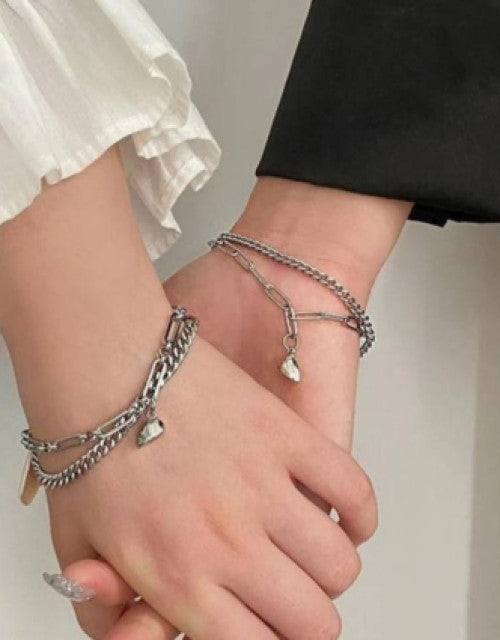 Silver chain bracelet for women worn on wrists featuring heart charms and layered design