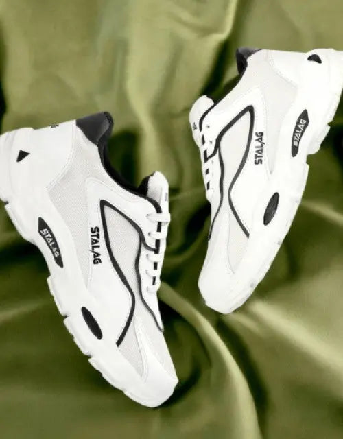 QuickGadgets men's white sports shoes with black accents and durable soles on green fabric background