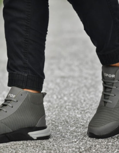 Gray sporty trendy men's sneakers India worn with black pants on asphalt surface